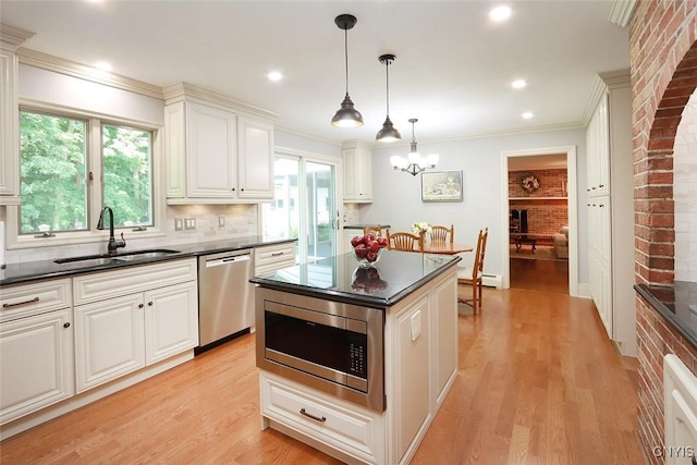 kitchen with sink, crown molding, appliances with stainless steel finishes, white cabinetry, and hanging light fixtures