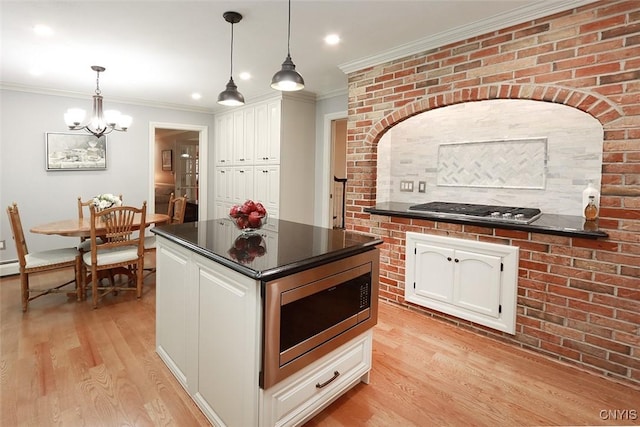 kitchen with appliances with stainless steel finishes, pendant lighting, white cabinetry, light hardwood / wood-style floors, and crown molding