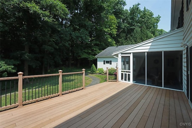 wooden deck with a lawn and a sunroom