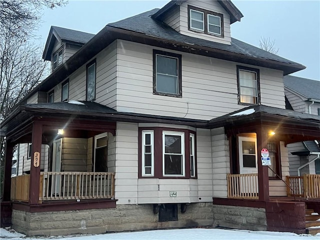 snow covered property with covered porch