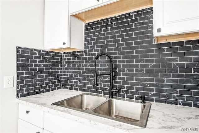 kitchen featuring white cabinetry, sink, decorative backsplash, and light stone counters