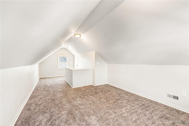 bonus room with lofted ceiling and light carpet