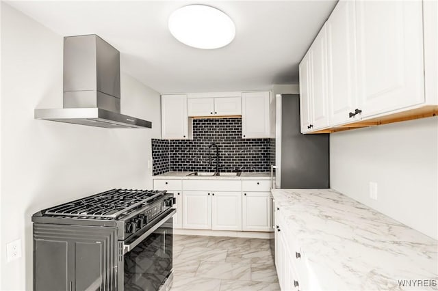 kitchen featuring tasteful backsplash, sink, white cabinets, gas range oven, and wall chimney exhaust hood