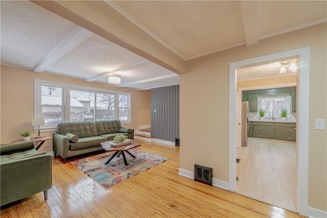 living room with sink, light hardwood / wood-style flooring, and beamed ceiling