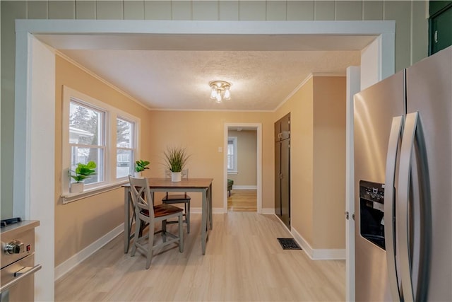 dining area featuring ornamental molding, a textured ceiling, and light hardwood / wood-style flooring