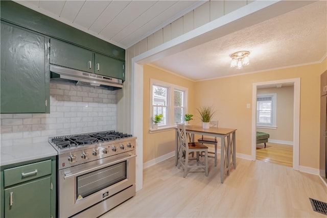 kitchen featuring crown molding, stainless steel range with gas cooktop, green cabinets, and backsplash