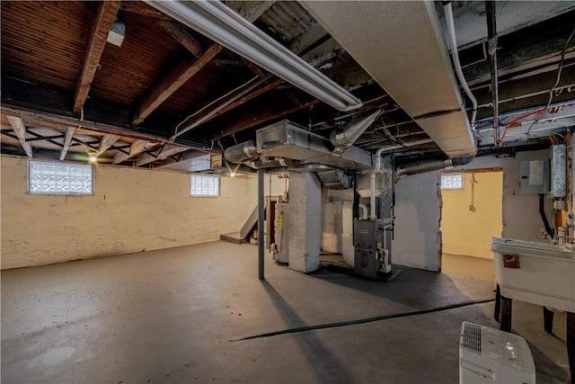 basement featuring gas water heater, sink, heating unit, and electric panel