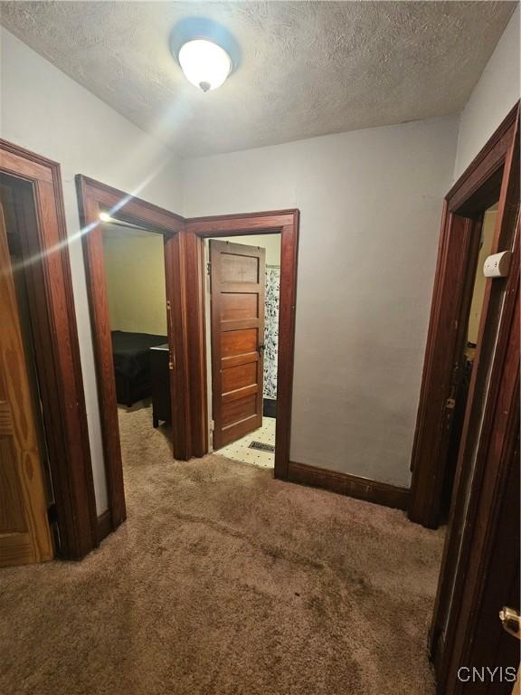 hallway featuring carpet floors and a textured ceiling