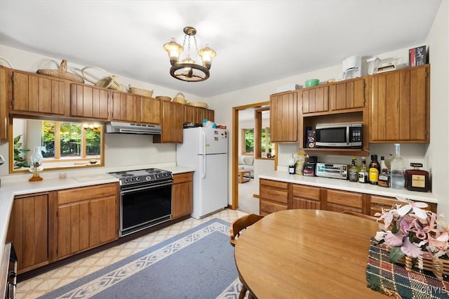 kitchen featuring a notable chandelier, range with electric cooktop, hanging light fixtures, and white refrigerator