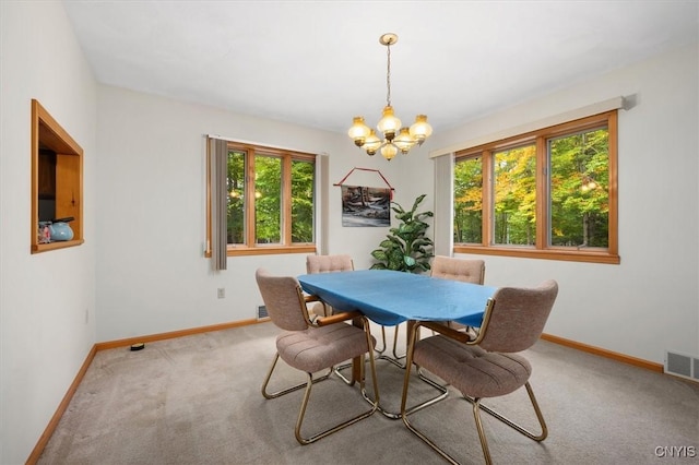 carpeted dining area featuring a healthy amount of sunlight and a chandelier