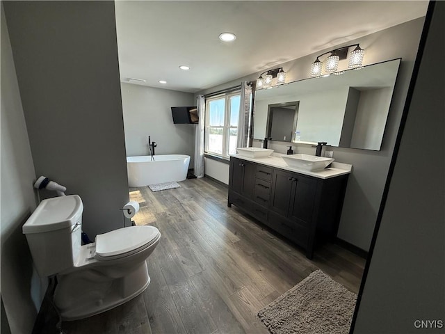 bathroom with vanity, a bath, wood-type flooring, and toilet