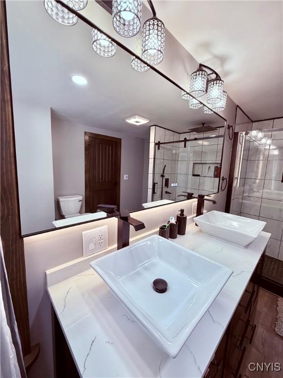 bathroom with vanity, tiled shower, and toilet