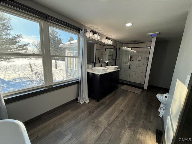 bathroom with vanity, hardwood / wood-style floors, toilet, and tiled shower