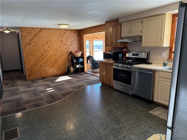 kitchen featuring stainless steel appliances and wood walls