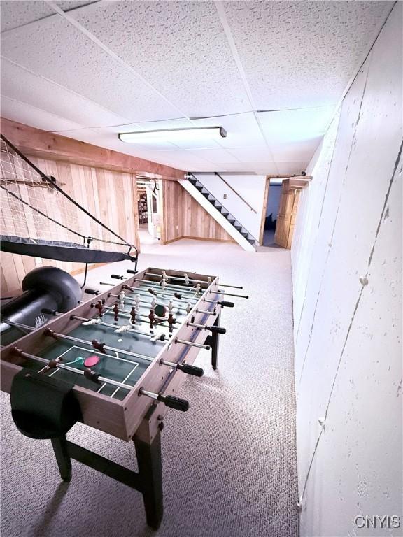 game room featuring a drop ceiling and wood walls