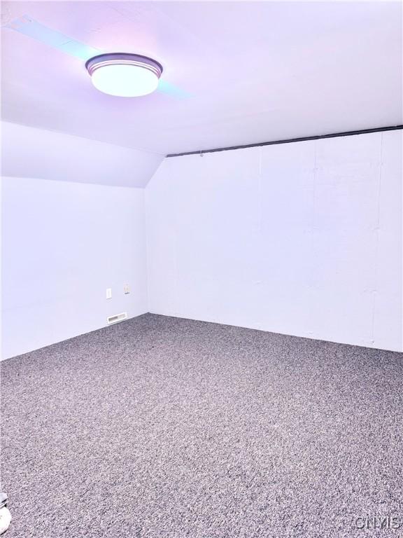 additional living space featuring lofted ceiling and carpet