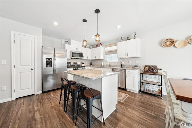 kitchen with stainless steel appliances, white cabinetry, a center island, and decorative light fixtures