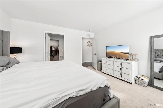 carpeted bedroom featuring a spacious closet and a closet