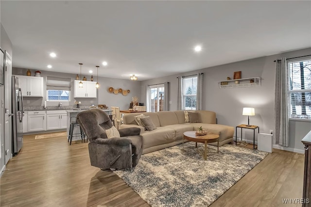 living room featuring sink, light hardwood / wood-style flooring, and a healthy amount of sunlight