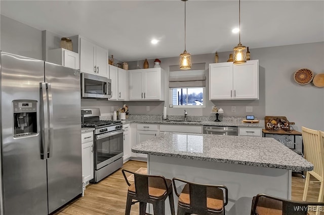 kitchen featuring sink, a kitchen island, pendant lighting, stainless steel appliances, and white cabinets