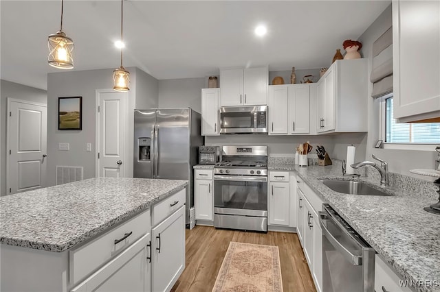 kitchen with sink, light hardwood / wood-style flooring, stainless steel appliances, white cabinets, and a kitchen island