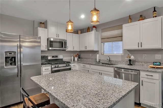 kitchen with pendant lighting, appliances with stainless steel finishes, sink, and white cabinets