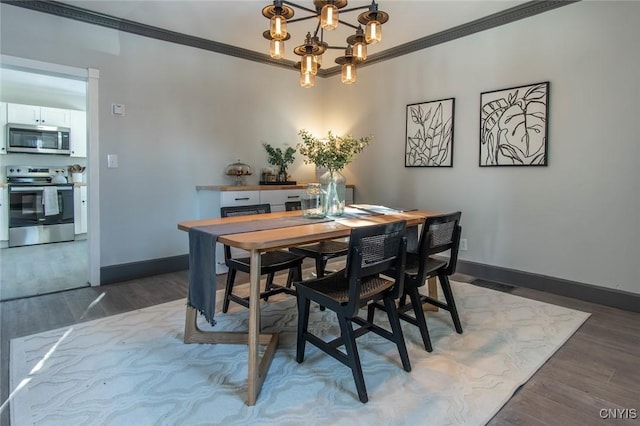 dining room with hardwood / wood-style flooring, crown molding, and an inviting chandelier