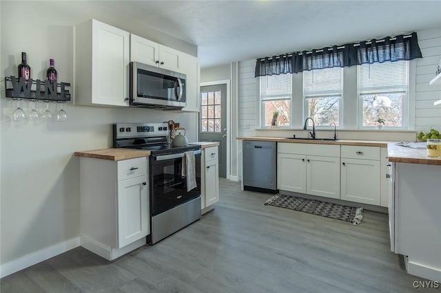 kitchen featuring appliances with stainless steel finishes, white cabinets, and butcher block countertops