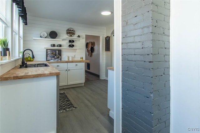 kitchen featuring butcher block countertops, light hardwood / wood-style floors, sink, and white cabinets