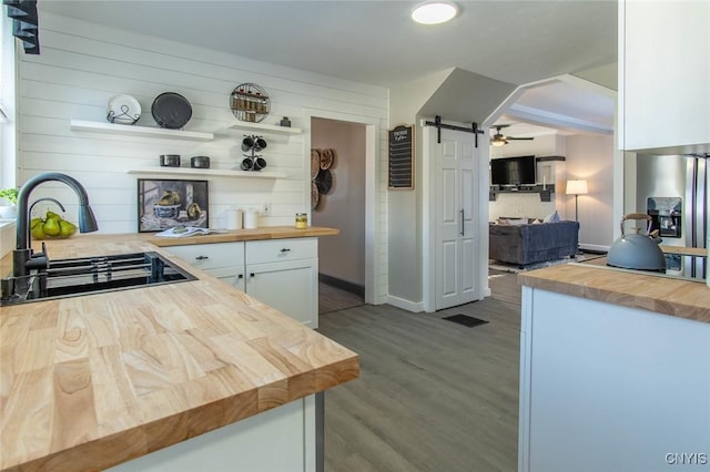 kitchen featuring wood counters, sink, wood-type flooring, a barn door, and white cabinets