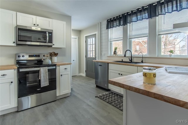 kitchen featuring wood counters, white cabinetry, and stainless steel appliances