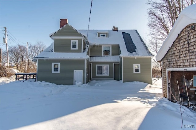 snow covered rear of property featuring a garage