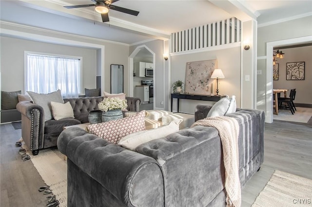 living room featuring ornamental molding, ceiling fan, and light wood-type flooring