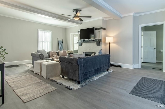 living room with crown molding, ceiling fan, hardwood / wood-style floors, and a brick fireplace