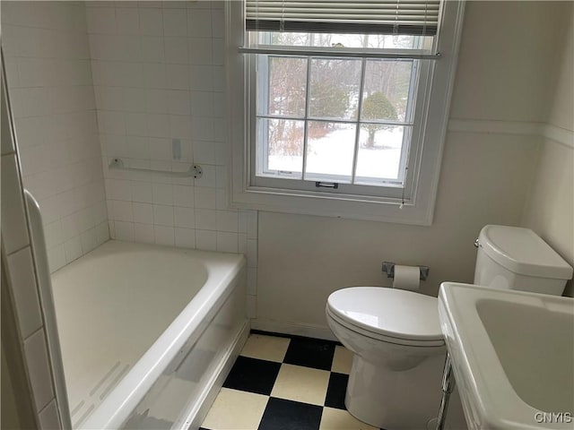 bathroom featuring sink, a tub, and toilet