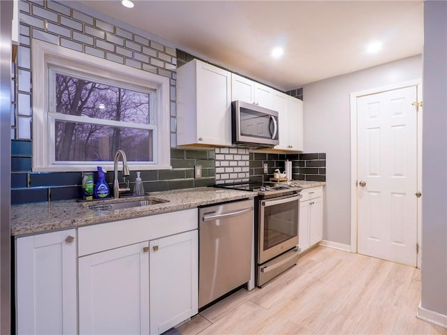 kitchen featuring white cabinetry, appliances with stainless steel finishes, light stone countertops, and sink