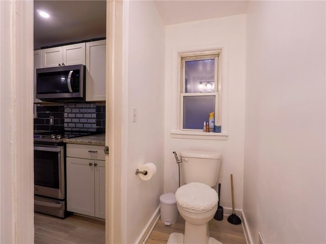 bathroom featuring hardwood / wood-style flooring, vanity, toilet, and backsplash