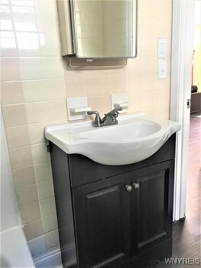 bathroom with decorative backsplash, vanity, and tile walls