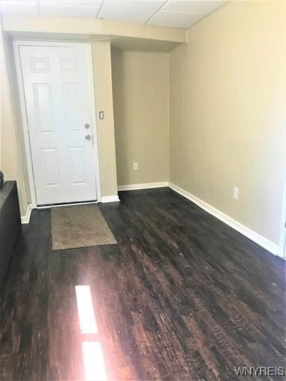 interior space with dark wood-type flooring and a drop ceiling