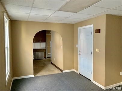 unfurnished room featuring radiator, a paneled ceiling, and carpet