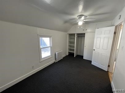 unfurnished bedroom featuring vaulted ceiling, radiator heating unit, ceiling fan, and a closet