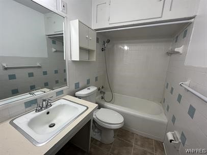 full bathroom with tiled shower / bath, sink, tile walls, toilet, and tile patterned floors