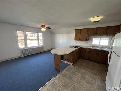 kitchen featuring white refrigerator, radiator heating unit, vaulted ceiling, and plenty of natural light