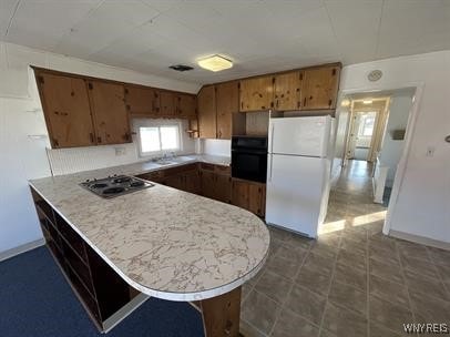 kitchen featuring white refrigerator, oven, stainless steel gas stovetop, and kitchen peninsula