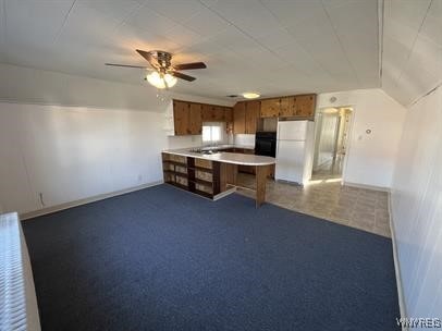 kitchen with lofted ceiling, white refrigerator, kitchen peninsula, ceiling fan, and oven