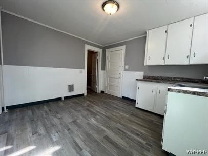 kitchen featuring dark wood-type flooring, crown molding, and white cabinets