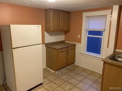 kitchen with light tile patterned floors, white fridge, and a textured ceiling