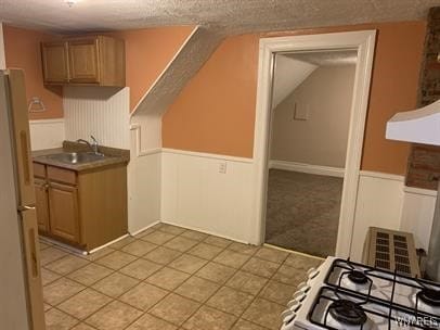 kitchen with a textured ceiling, sink, white fridge, and stove