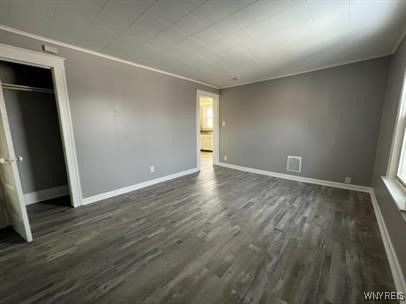 unfurnished bedroom featuring ornamental molding, dark hardwood / wood-style floors, and a closet