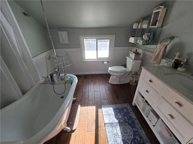 bathroom with wood-type flooring, toilet, vanity, and a tub to relax in